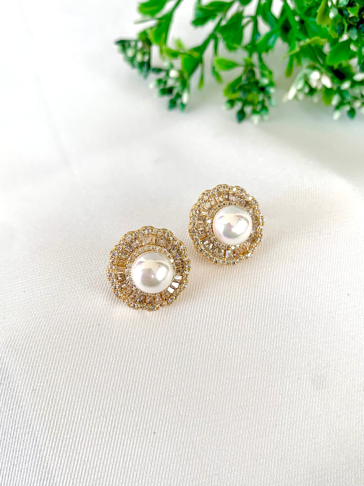 Classic gold and pearl earrings styled flat lay on white background