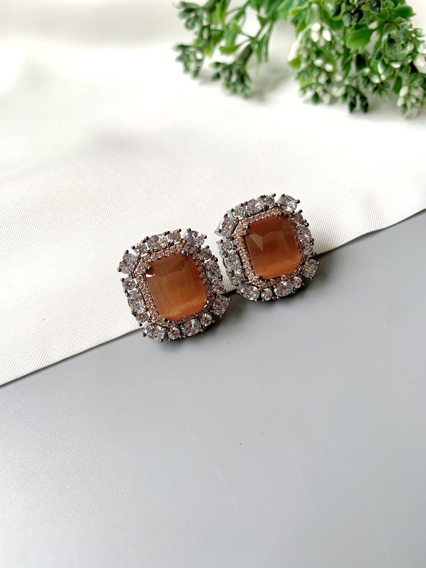 Pair of handcrafted Onyx stud earrings with oxidized black rose plating, displayed on white fabric backdrop