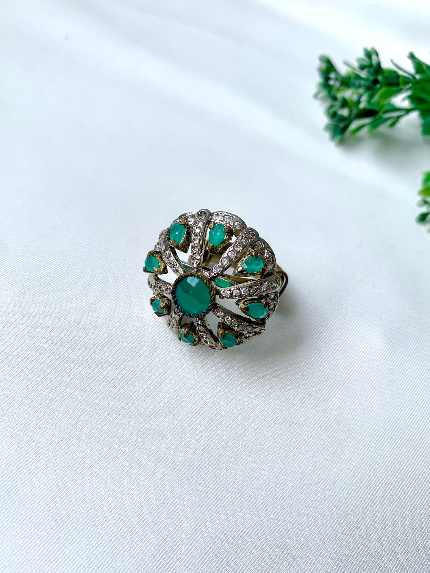 Close-up of Selene Bloom Ring with Semi-Precious Emerald stones and American Diamonds in antique Victorian rhodium finish, displayed on white fabric