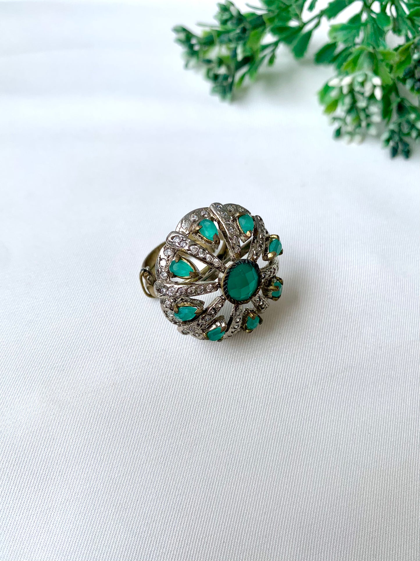 Close-up of Selene Bloom Ring with Semi-Precious Emerald stones and American Diamonds in antique Victorian rhodium finish, displayed on white fabric