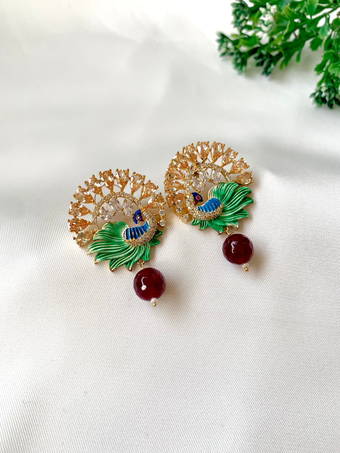 Decorative earrings with green leaves and red berries on a white background