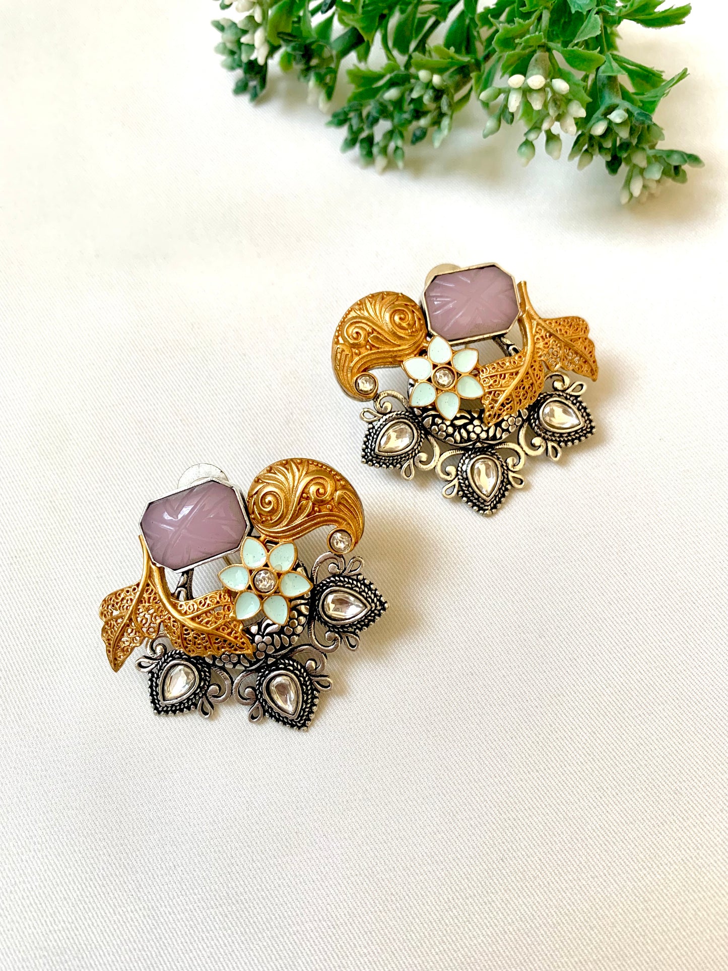 Pair of ornate earrings with gemstones on a light background