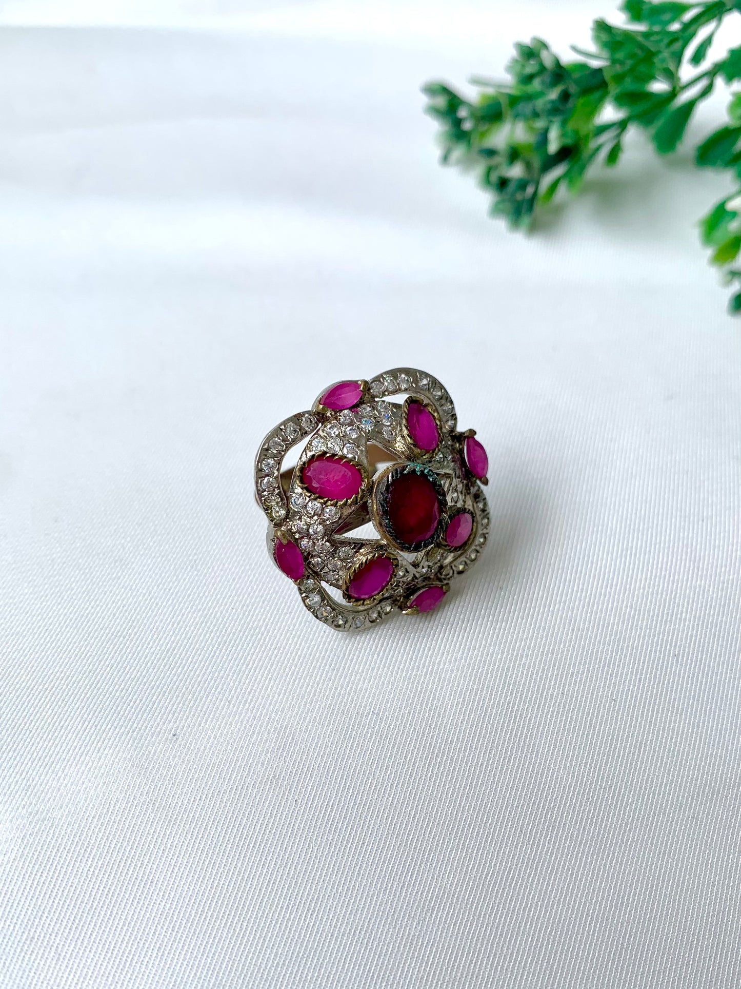 Handcrafted rhodium-plated Victorian-style ring with American Diamonds and semi-precious ruby stones on a white fabric backdrop