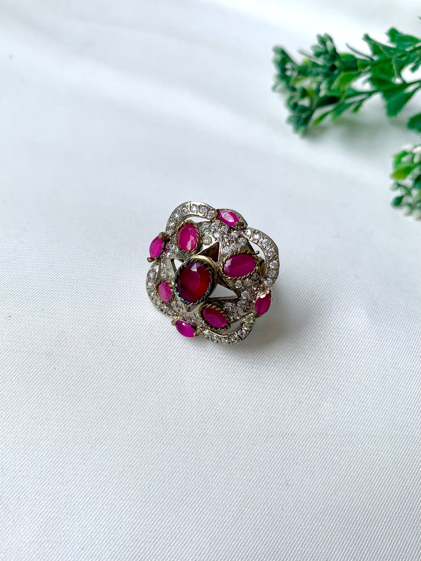 Handcrafted rhodium-plated Victorian-style ring with American Diamonds and semi-precious ruby stones on a white fabric backdrop