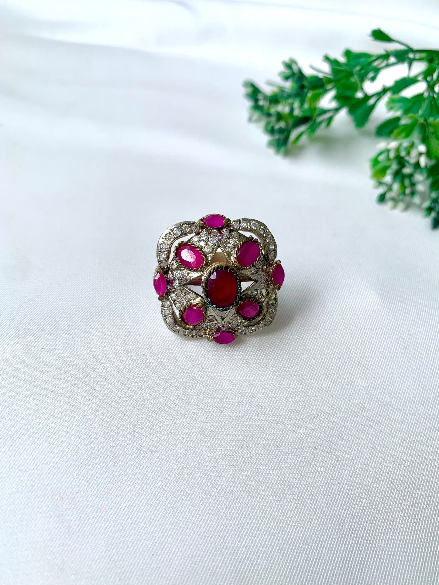 Handcrafted rhodium-plated Victorian-style ring with American Diamonds and semi-precious ruby stones on a white fabric backdrop