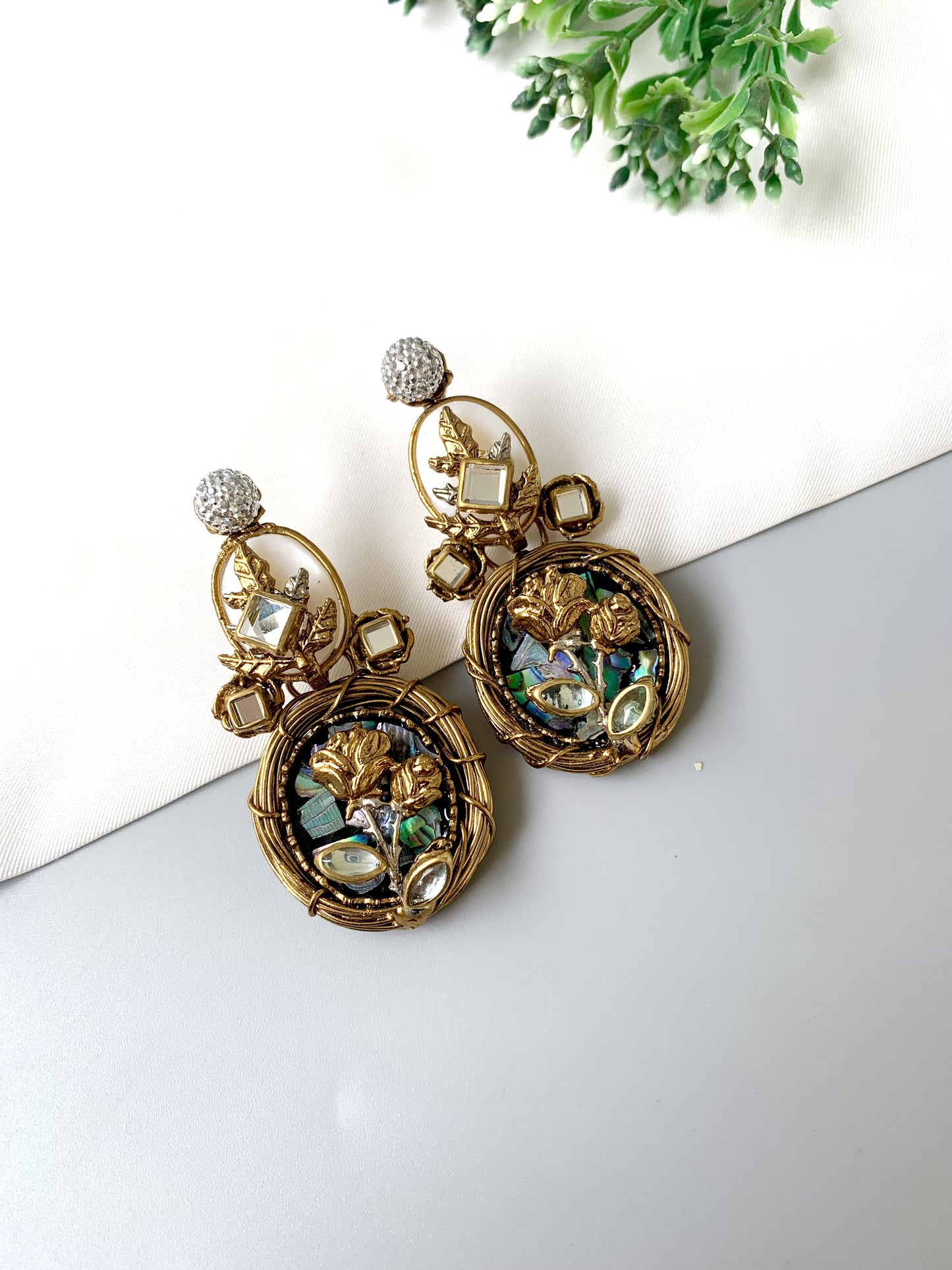 Close-up image of gold Elara Bloom earrings featuring intricate handcrafted floral elements with pearl and gemstone accents.