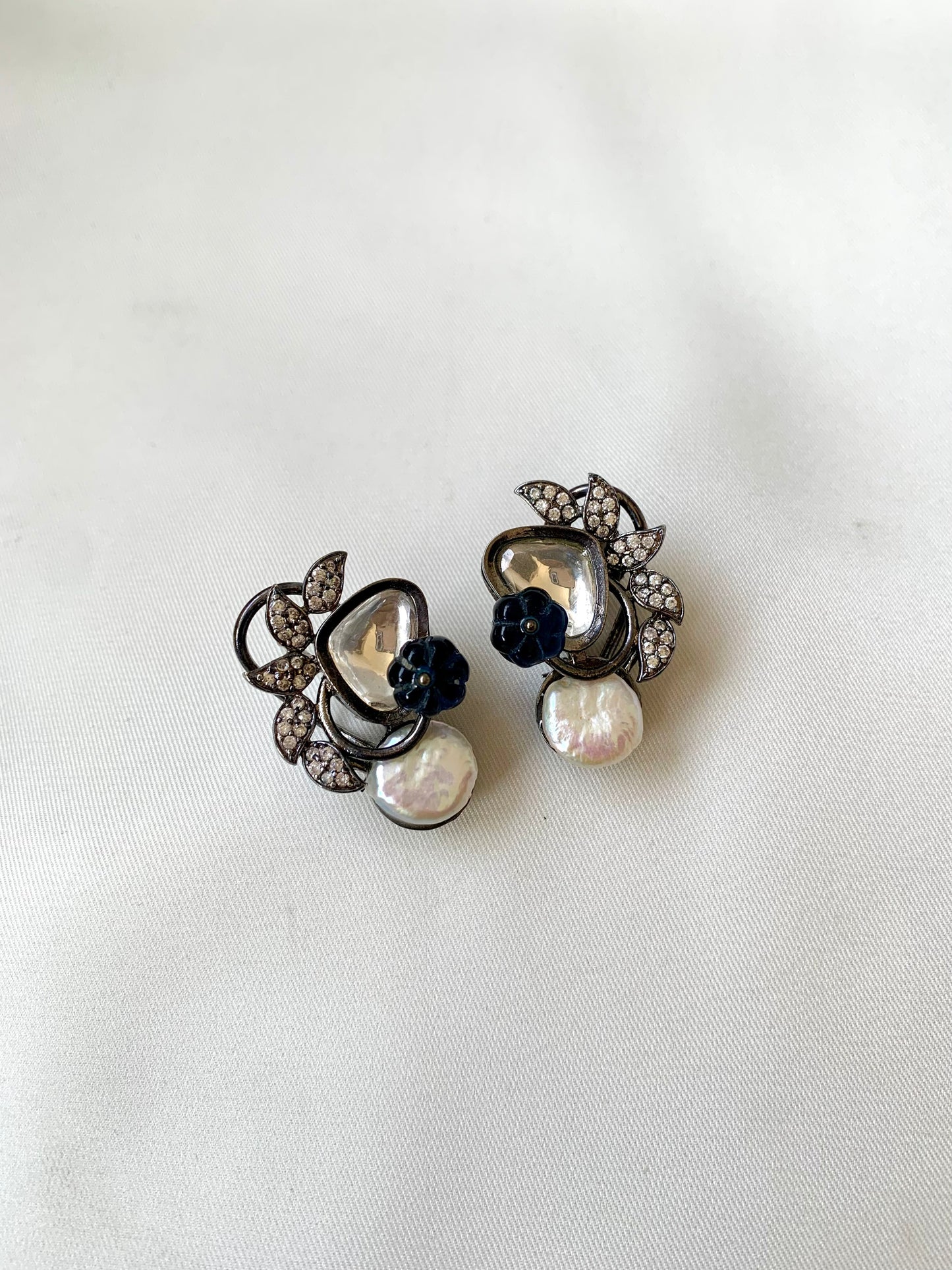 Pair of earrings with pearls and black stones on a white background
