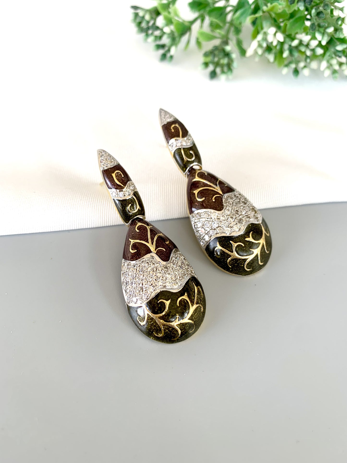 Flat lay of drop earrings featuring gold filigree Meena work and pave stones
