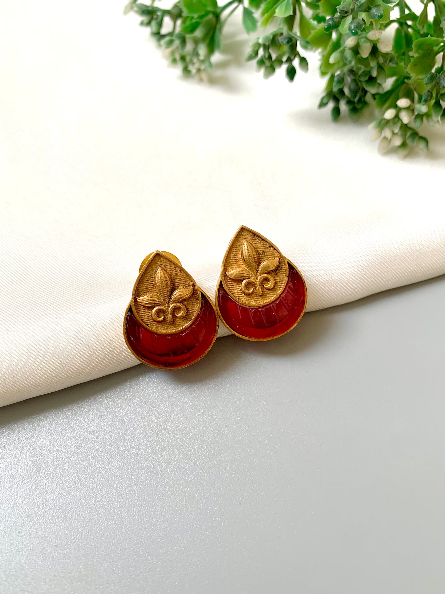 Ishani Studs with rich ruby stone and antique floral motif in matte gold finish – angled view.