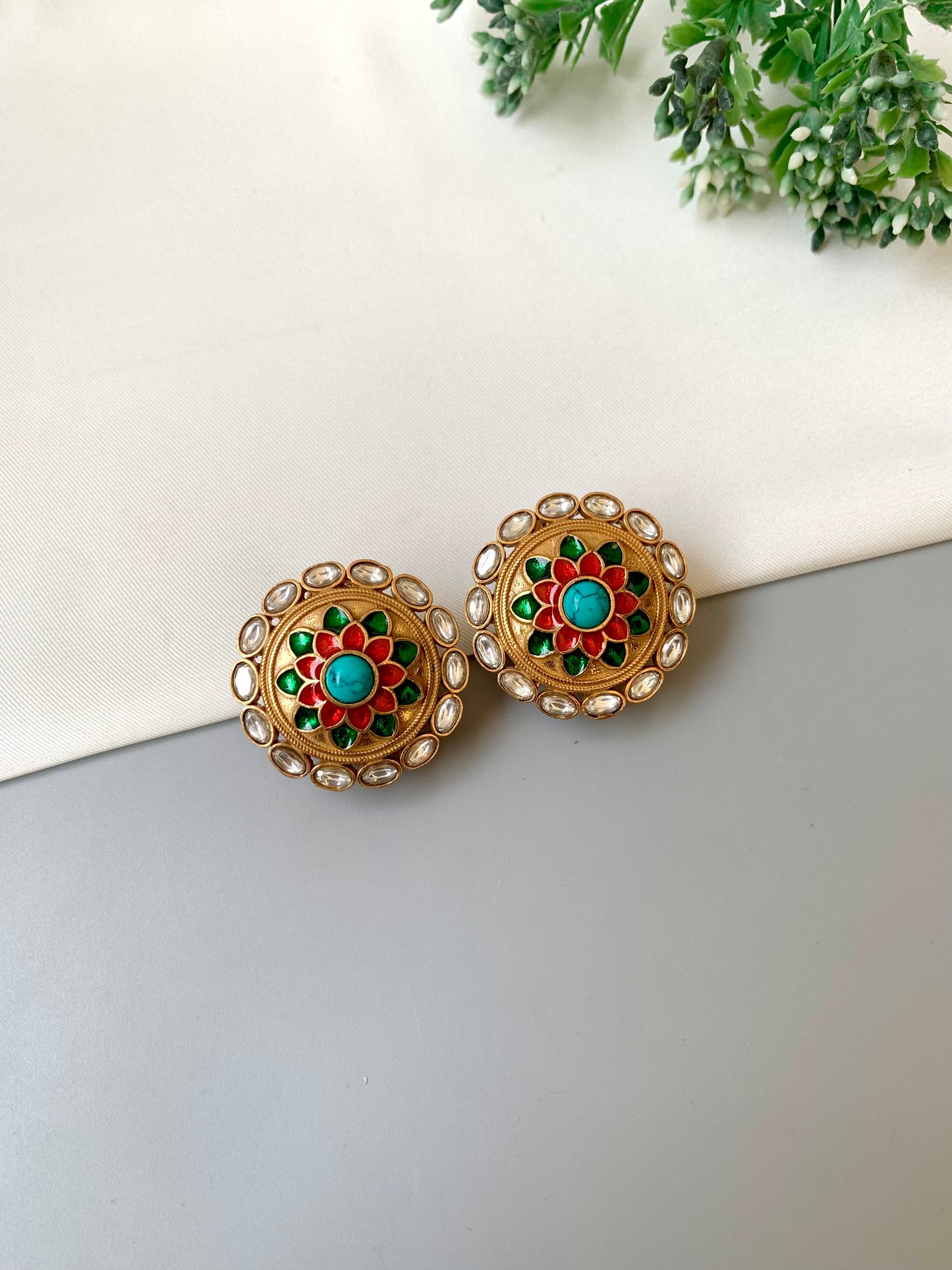 Pair of ornate earrings with colorful gemstones on a light background