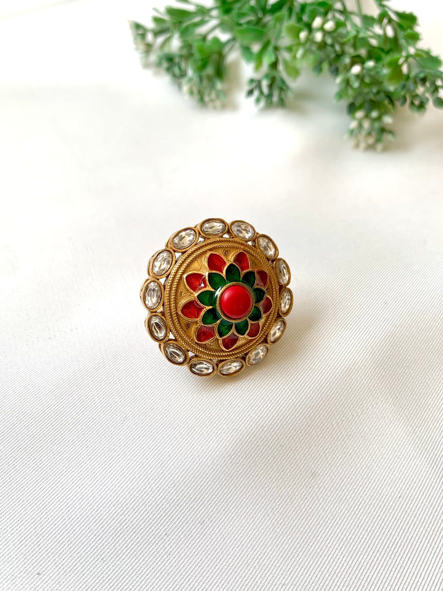 Decorative brooch with red and green center on a white background