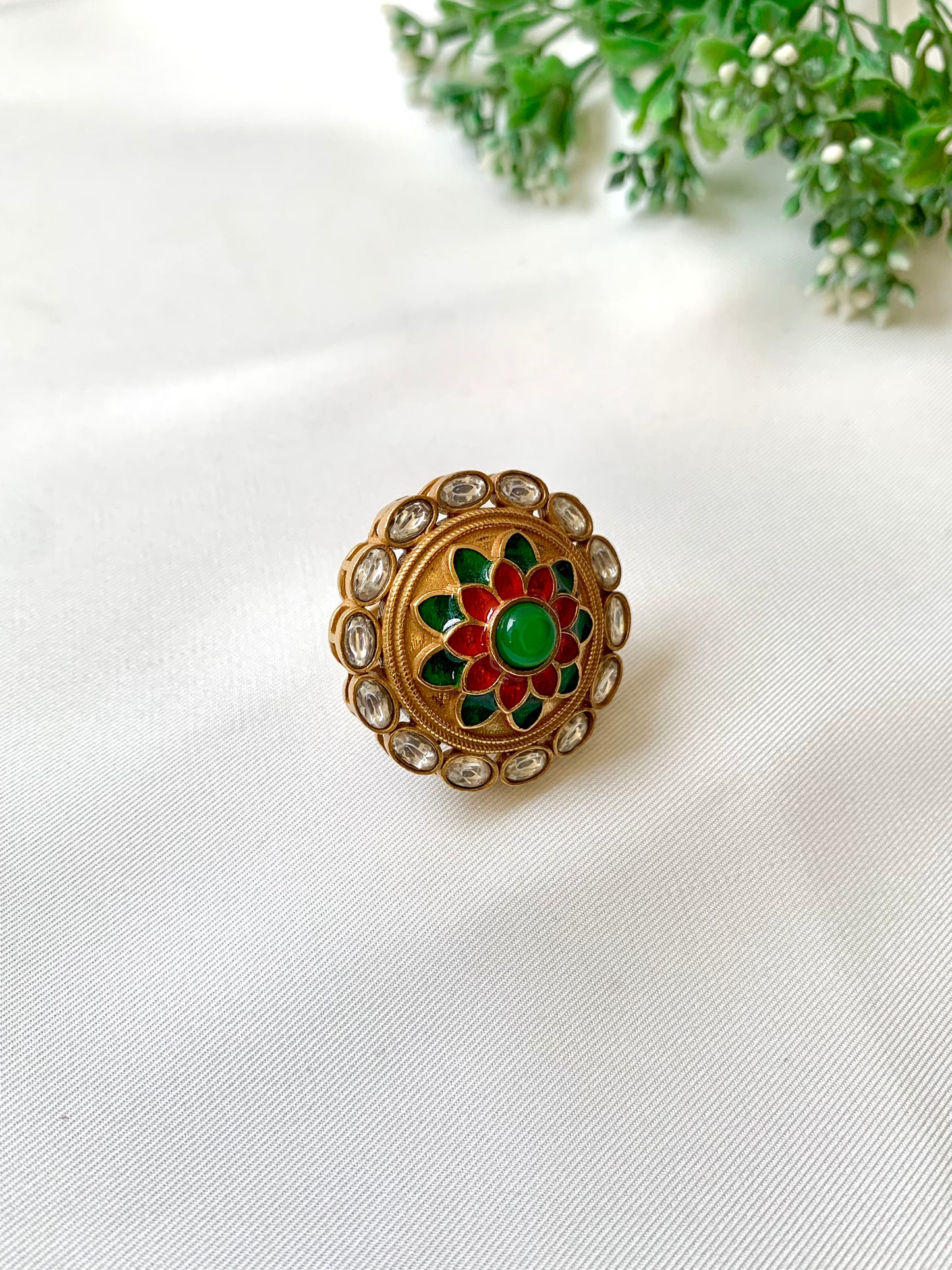 Decorative brooch with green gemstone on a white fabric background