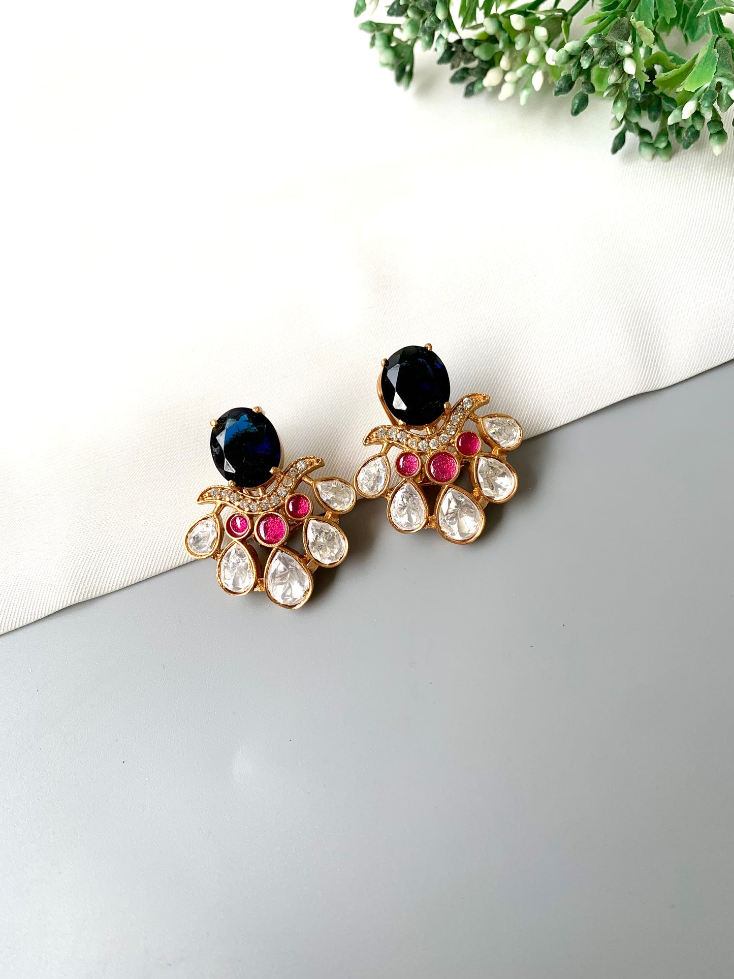 Top-angle shot of Kavia Sapphire earrings highlighting the bold blue and ruby combination in gold plating.