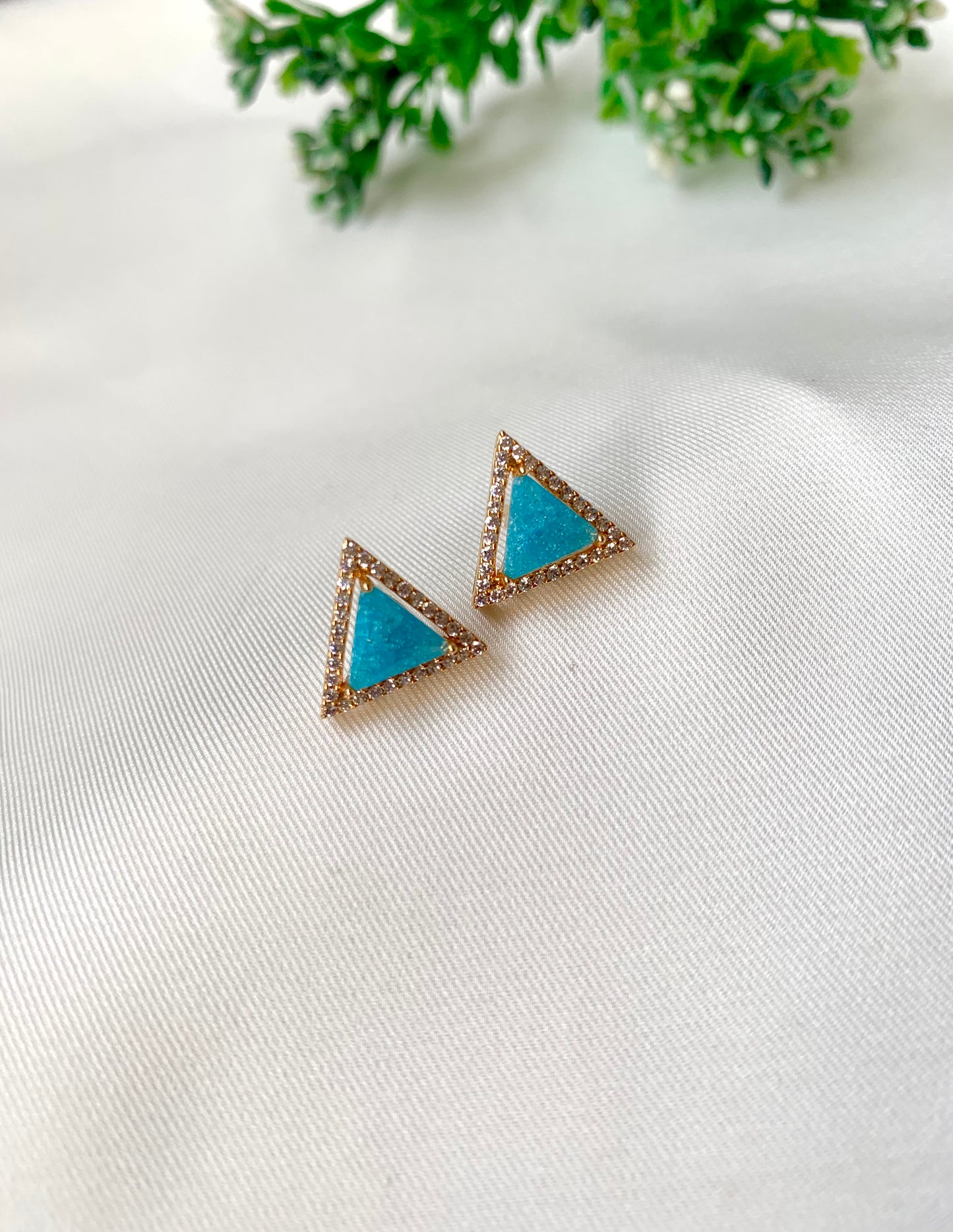 Triangle-shaped earrings with turquoise centers on a white background