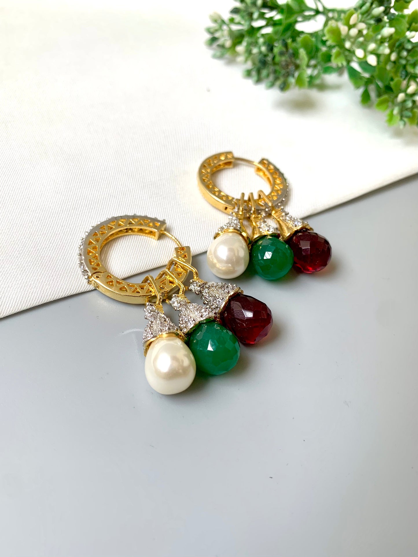 Convertible earrings featuring detachable drops in pearl, green emerald, and red ruby stones with diamond detailing