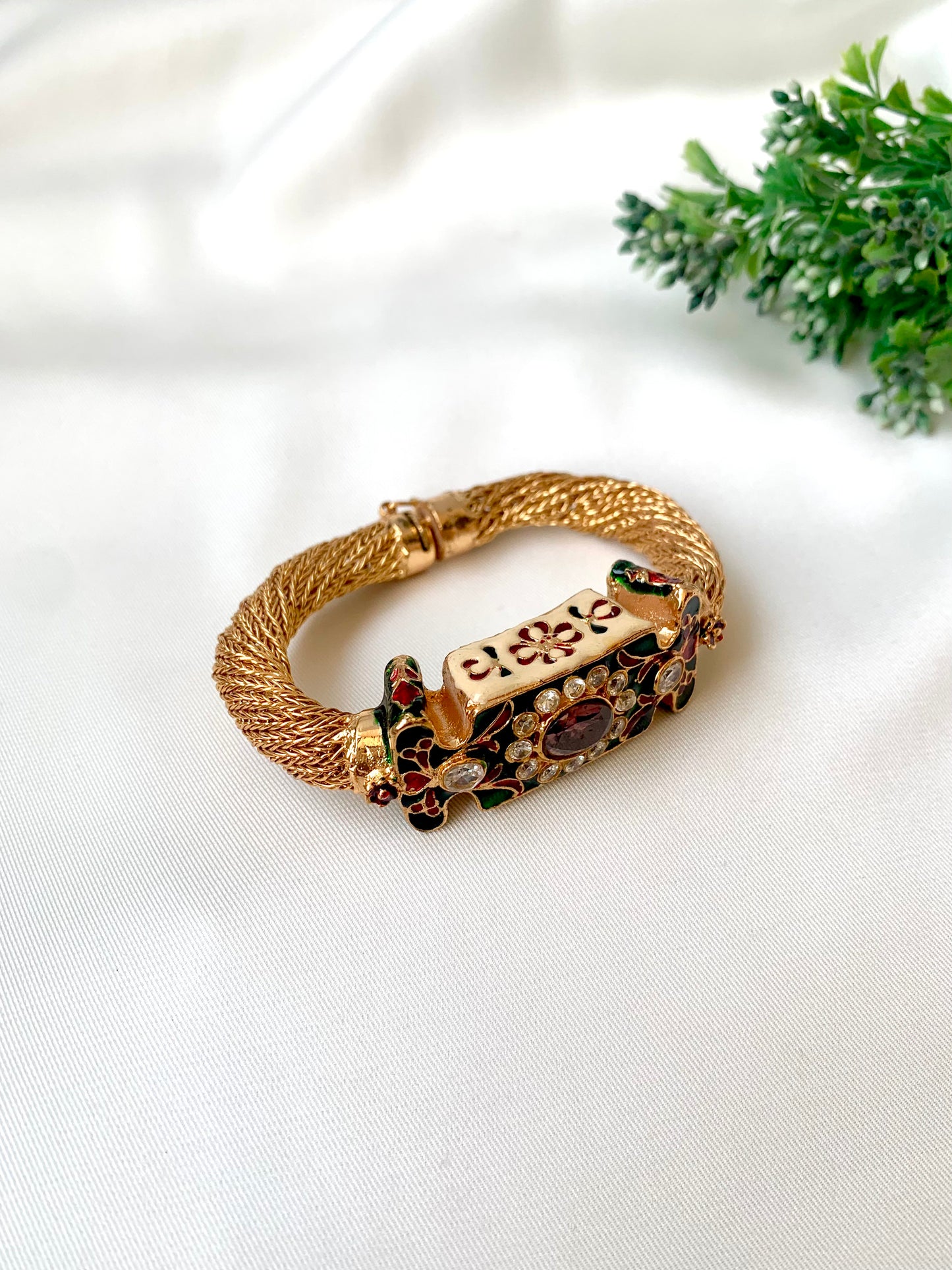 Gold bracelet with gemstones on a white fabric background