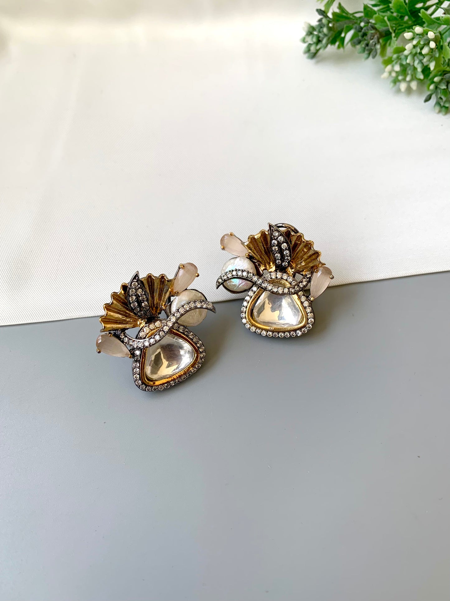 Pair of decorative earrings on a light surface with a blurred background