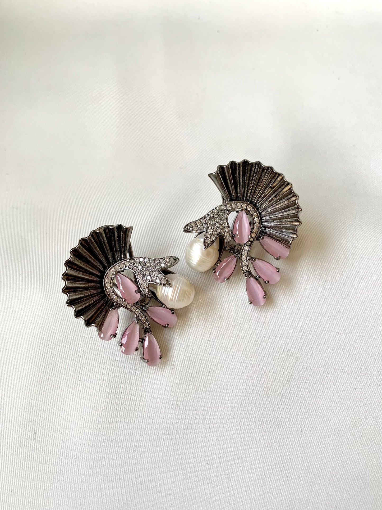 Pair of earrings with pink and pearl accents on a light background