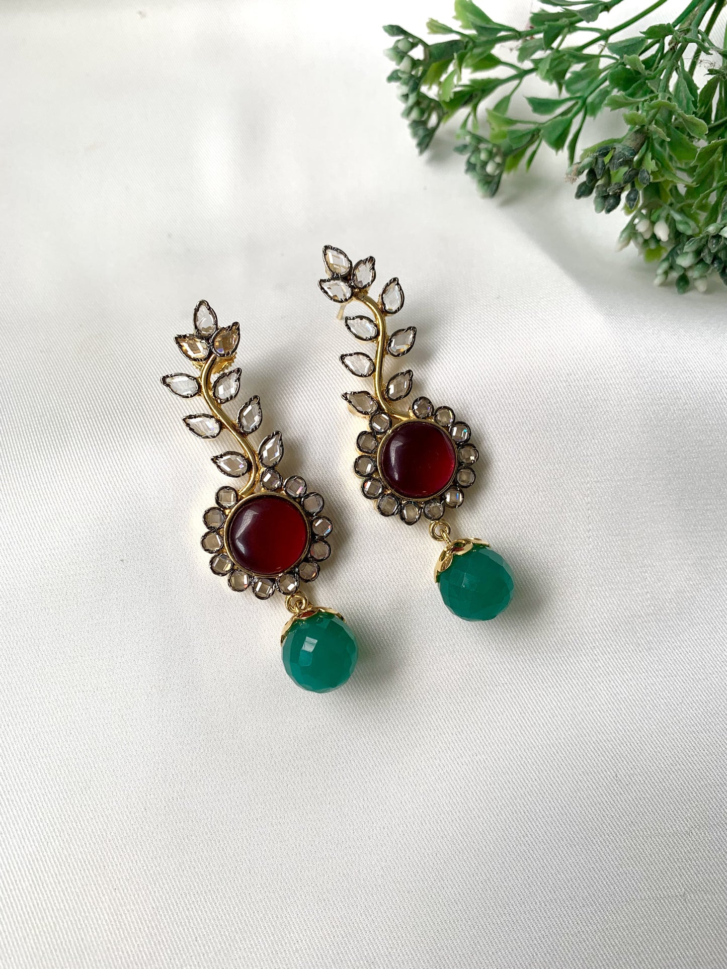 Pair of earrings with red and green stones on a white background