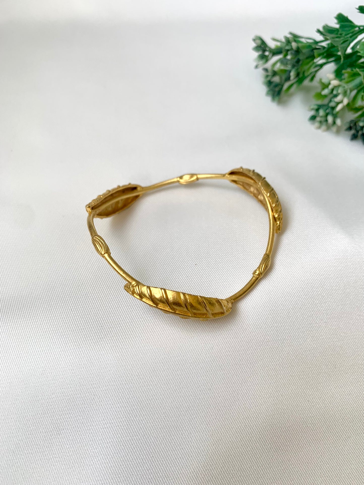 Rishani geometric gold bangle in curved triangular shape with hand carved leaf design