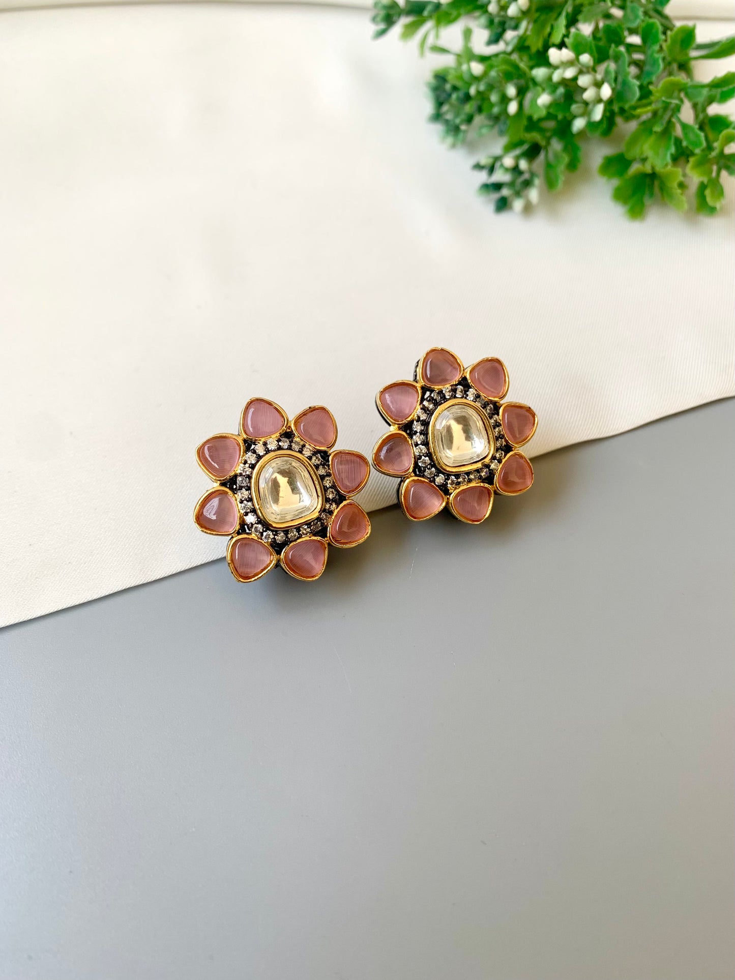 Pair of floral earrings with pink and gold details on a white surface.