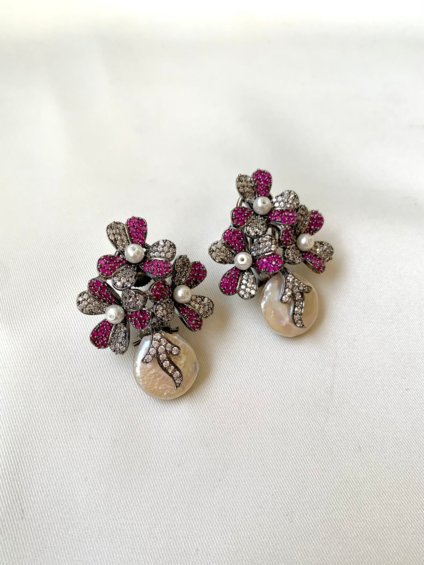 Pair of earrings with floral design and pearl-like beads on a white background