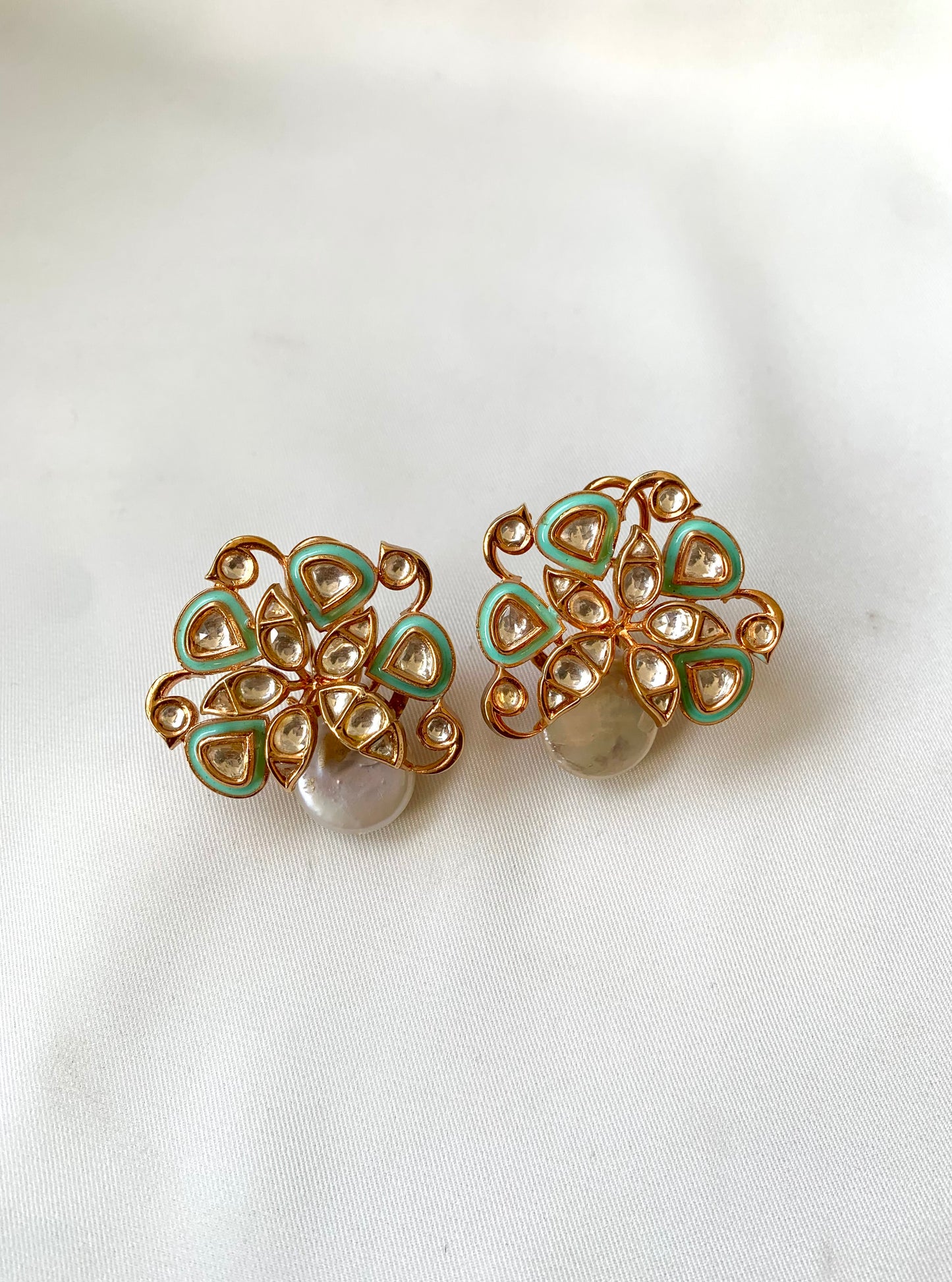 Pair of gold and green floral earrings on a white background