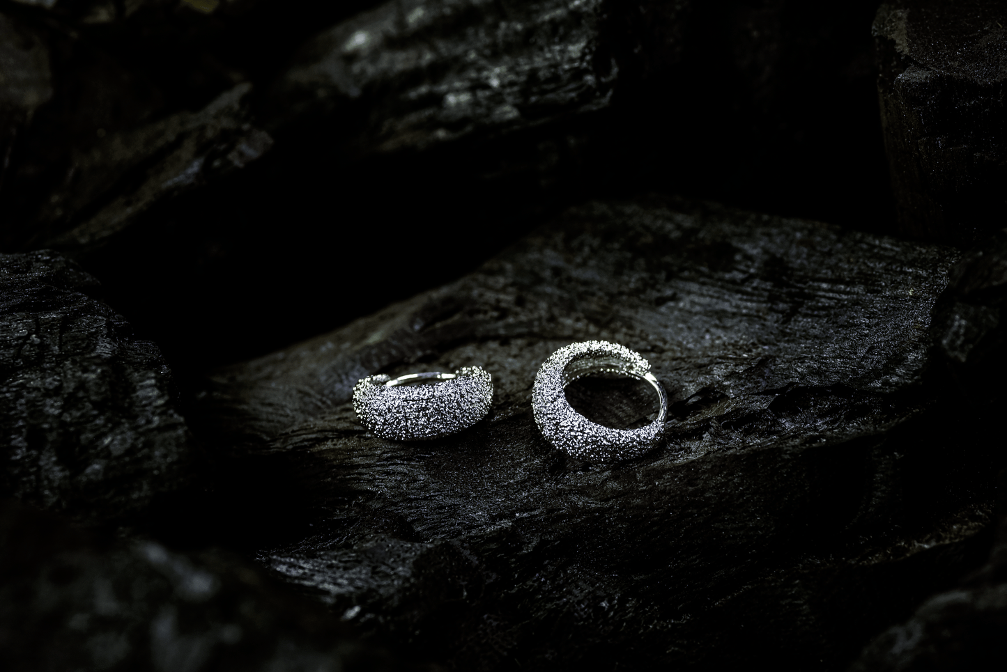 Handcrafted Venice Hoops with textured Rhodium plating in platinum finish displayed on a dark background