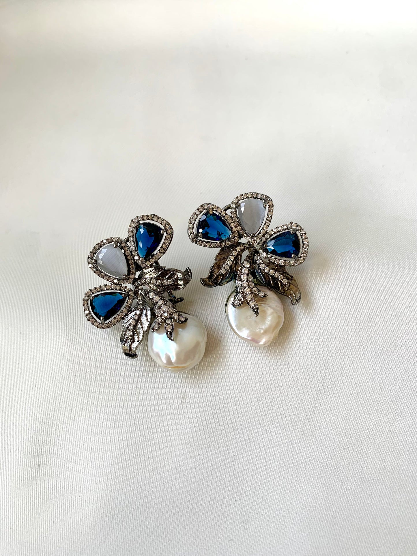 Pair of decorative earrings with blue and pearl elements on a white background