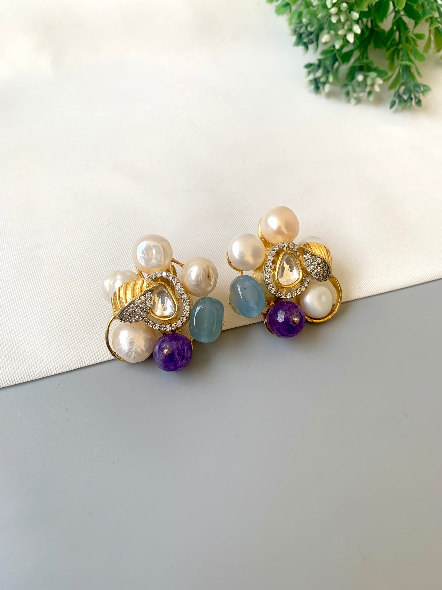 Pair of earrings with pearls and gemstones on a white surface.