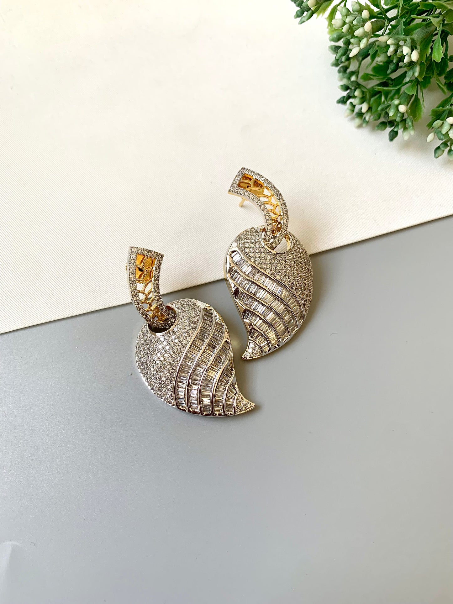 Pair of shell-shaped earrings with intricate designs on a light surface.
