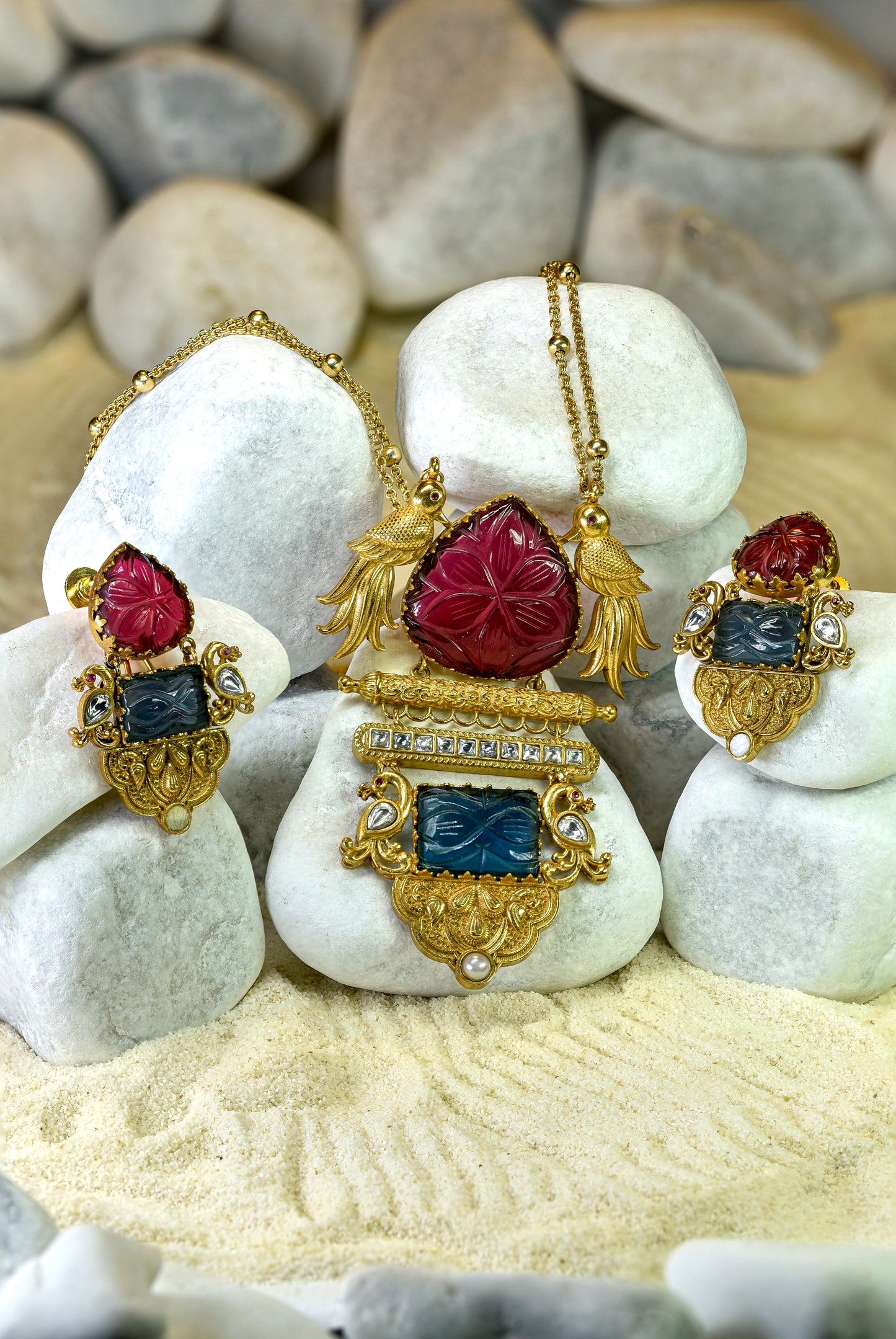 Ornate gold and gemstone jewelry set on white stones with a natural stone background