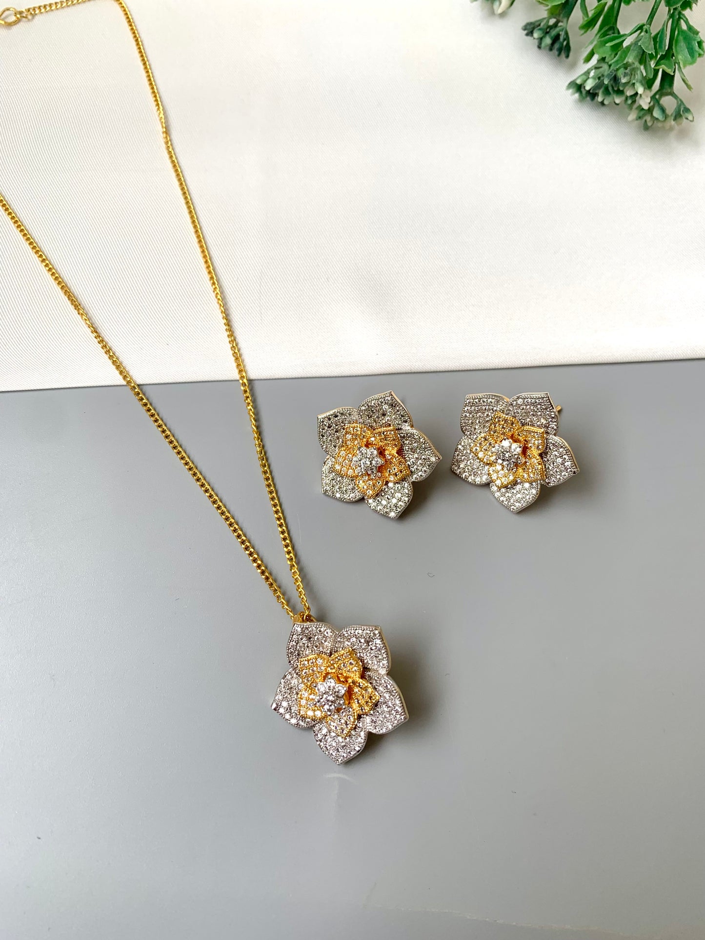 Floral jewelry set with necklace and earrings on a light gray surface.