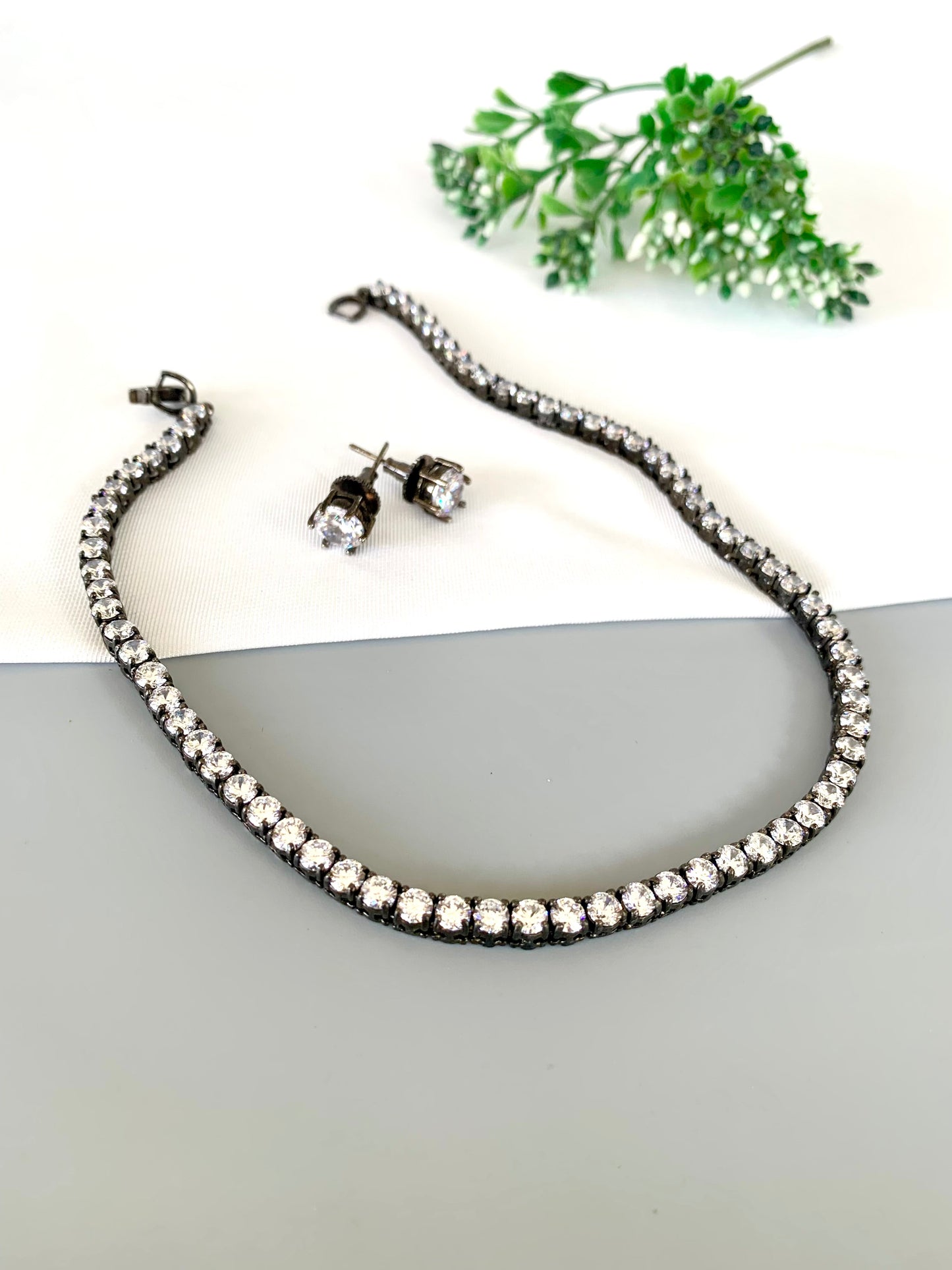 Flat lay of Zehra Necklace Set on white fabric with greenery in frame