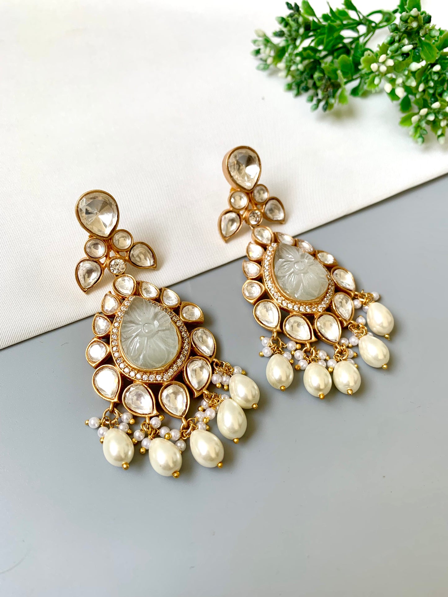 Close-up of Zoya ivory earrings featuring carved ivory stone, 22kt gold plating, and delicate pearl accents