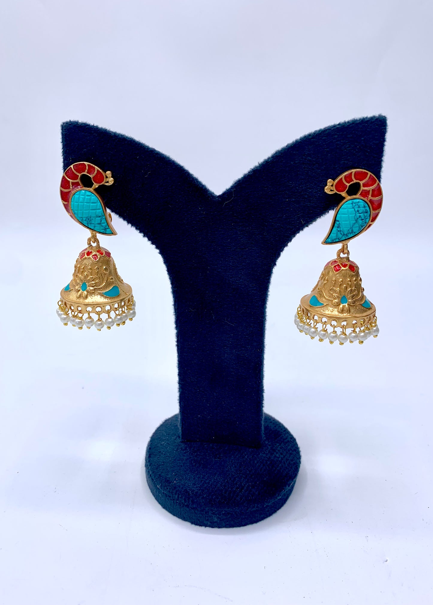 A pair of gold-plated earrings with blue and green stone accents and pearl drops, displayed on a Y-shaped stand.