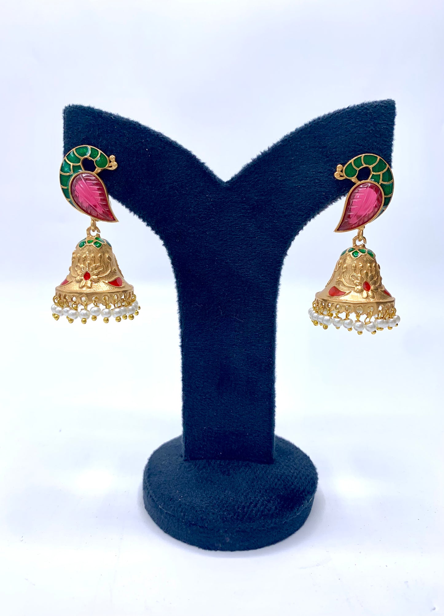 A pair of gold-plated earrings with hand-carved ruby and pearls displayed on a Y-shaped stand.