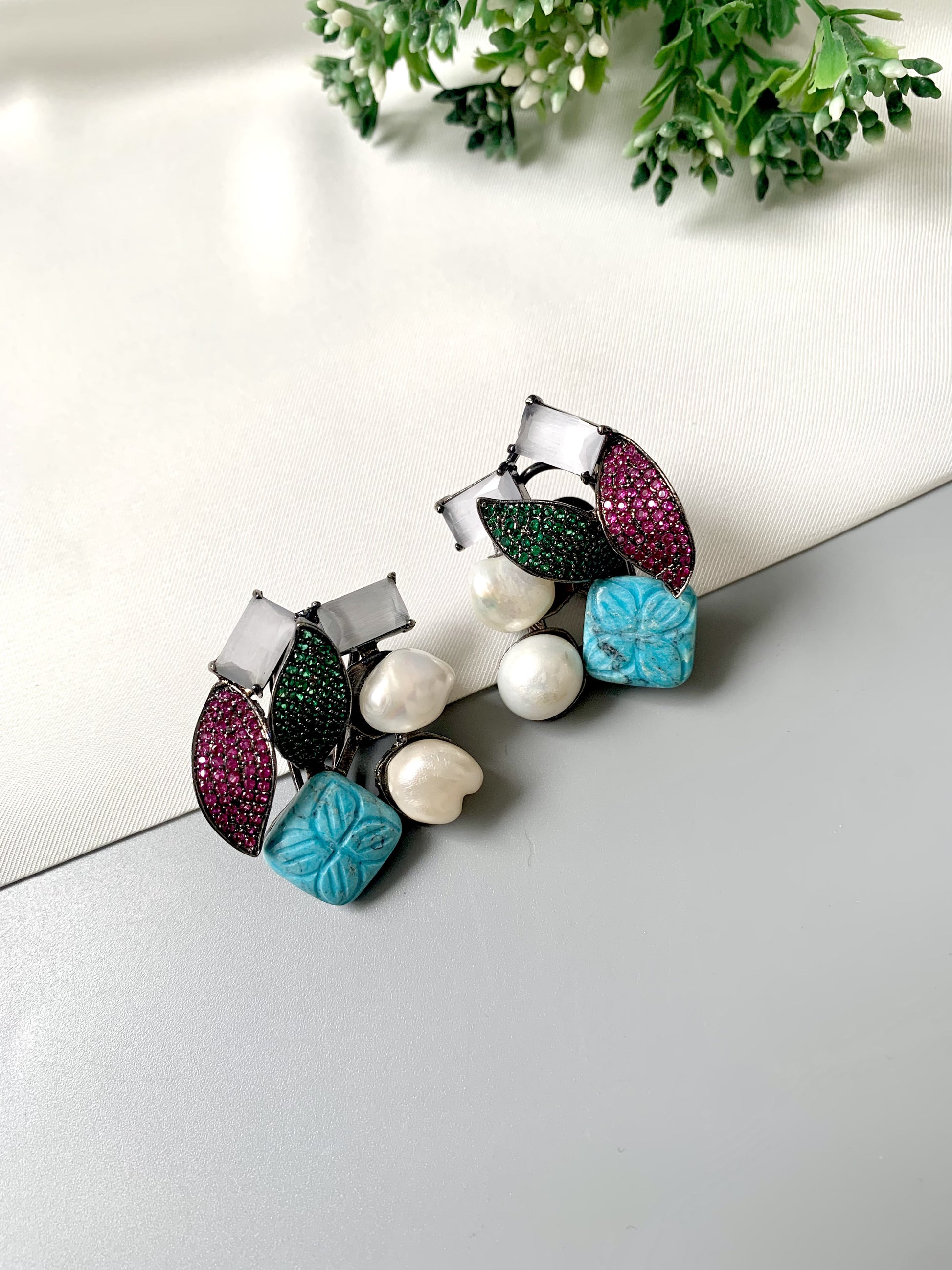 Rhodium oxidized black polish studs with semi-precious onyx, baroque pearls, ruby and emerald Swarovski crystals, and hand-carved turquoise feroza from Zamal Jewels