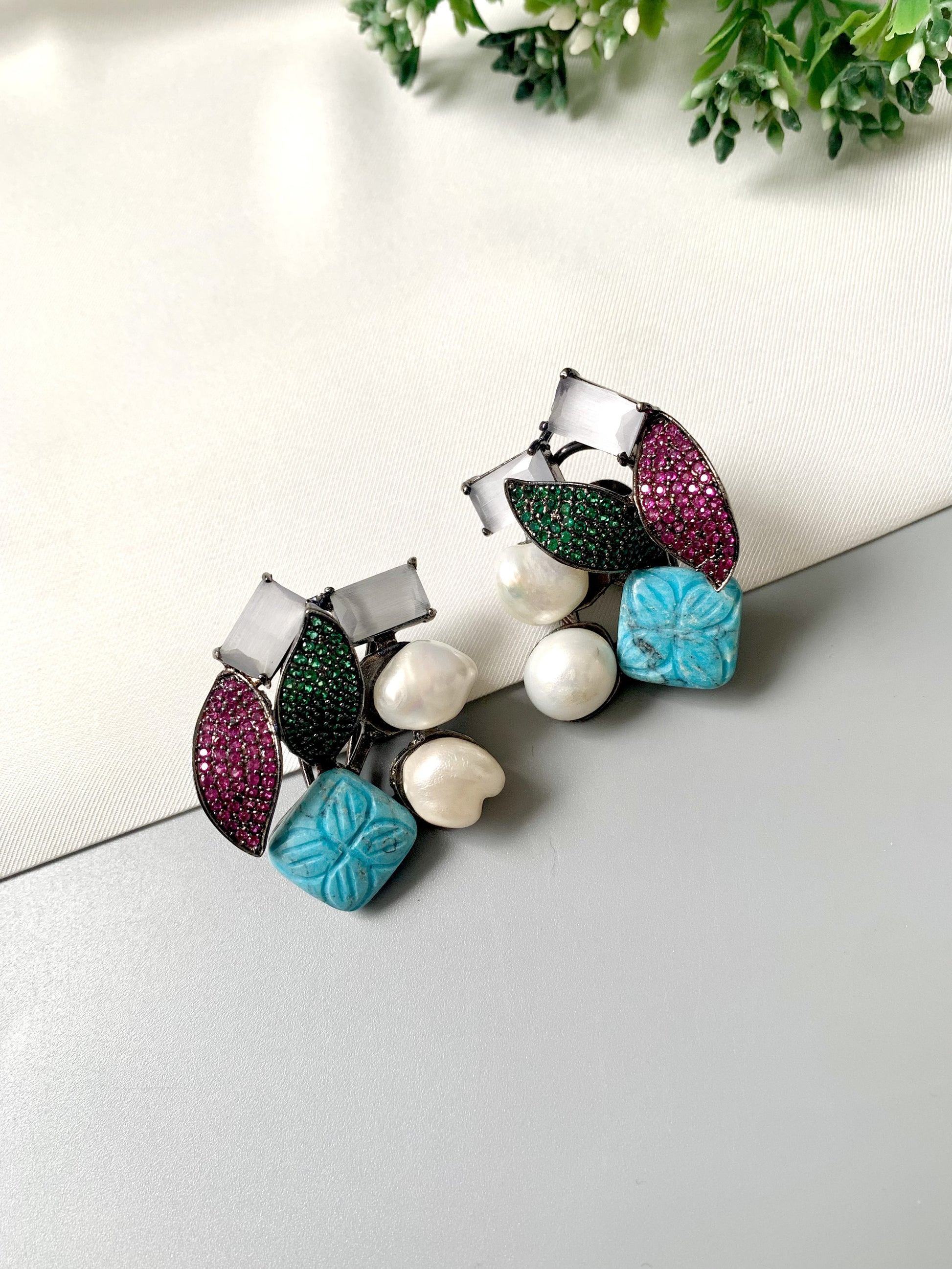 Rhodium oxidized black polish studs with semi-precious onyx, baroque pearls, ruby and emerald Swarovski crystals, and hand-carved turquoise feroza from Zamal Jewels