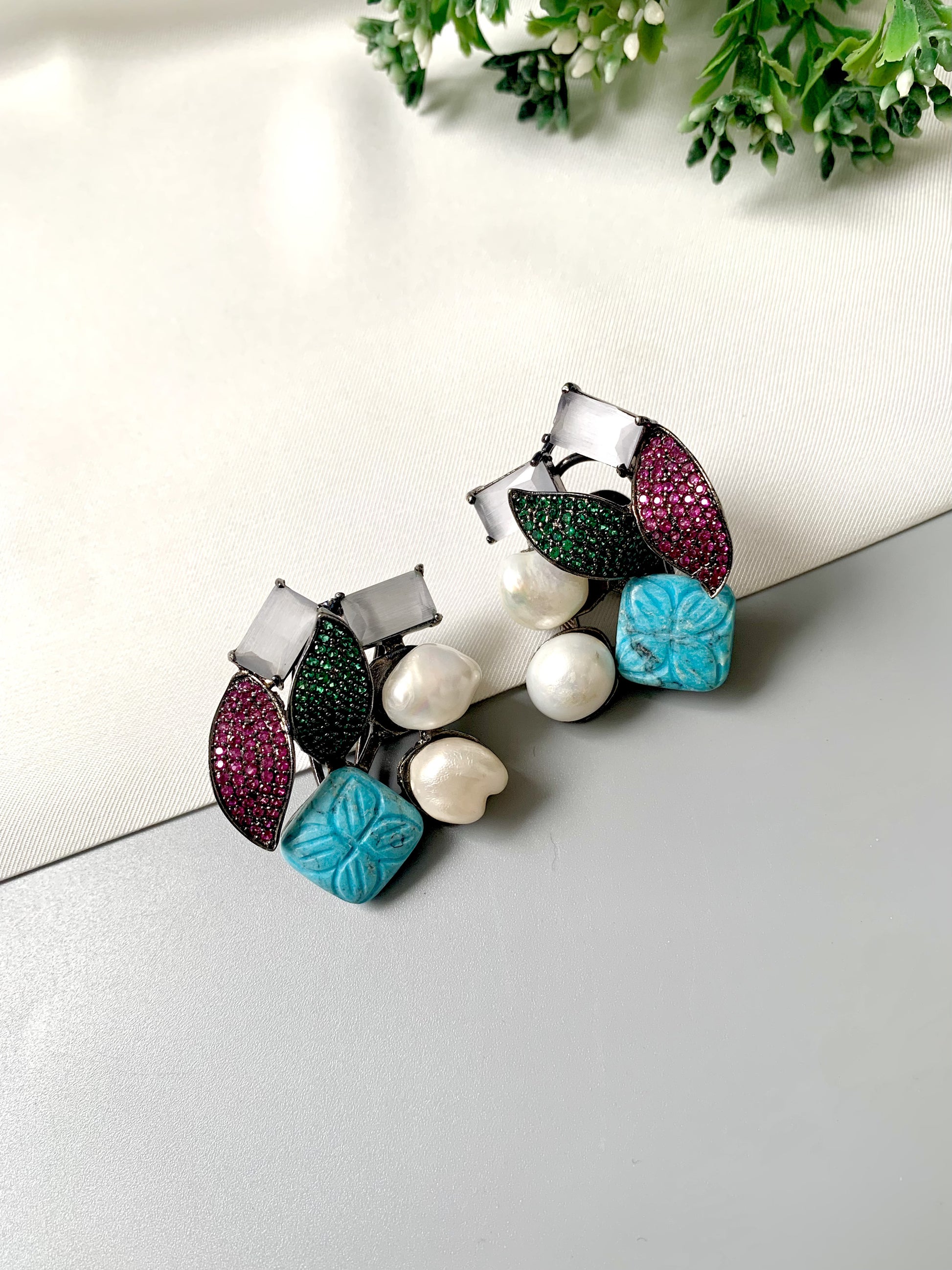 Rhodium oxidized black polish studs with semi-precious onyx, baroque pearls, ruby and emerald Swarovski crystals, and hand-carved turquoise feroza from Zamal Jewels