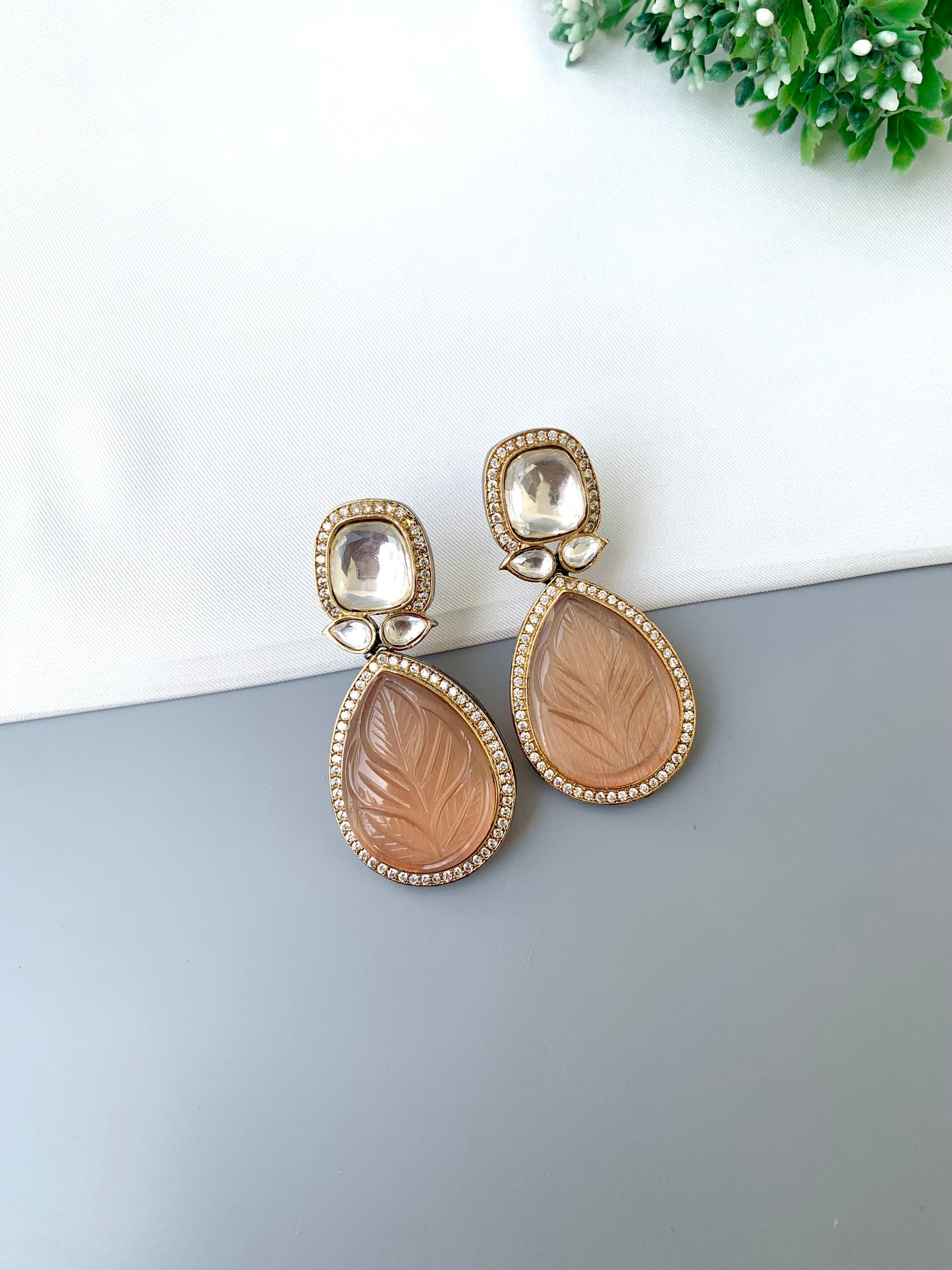 Pair of earrings with leaf design on a white and gray surface.