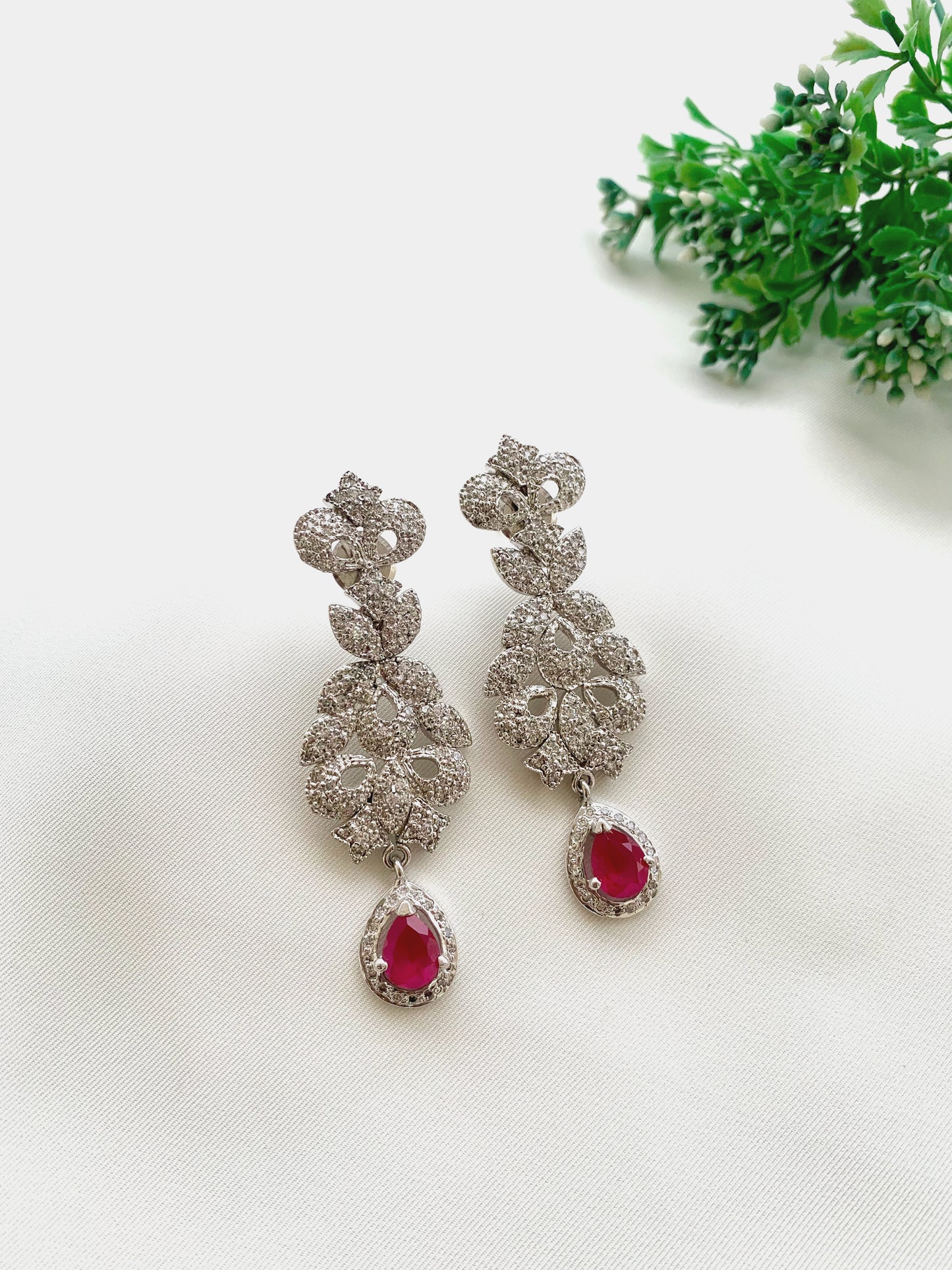 Gehna handcrafted rhodium plated earrings with a diamond finish featuring American Diamonds and semi-precious Ruby