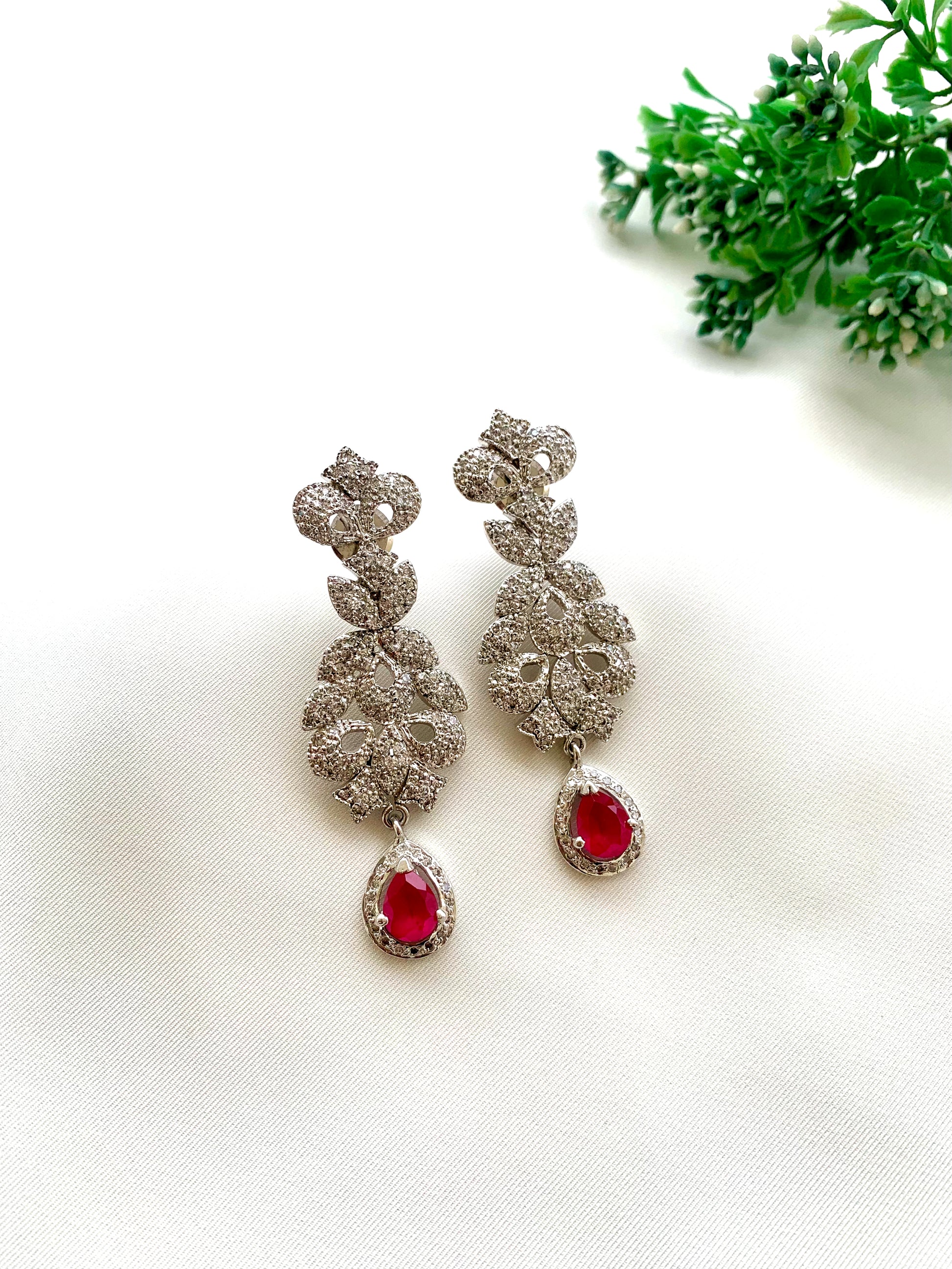 Gehna handcrafted rhodium plated earrings with a diamond finish featuring American Diamonds and semi-precious Ruby