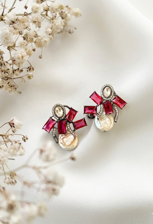 Ornate earrings with red and gold accents on a light background