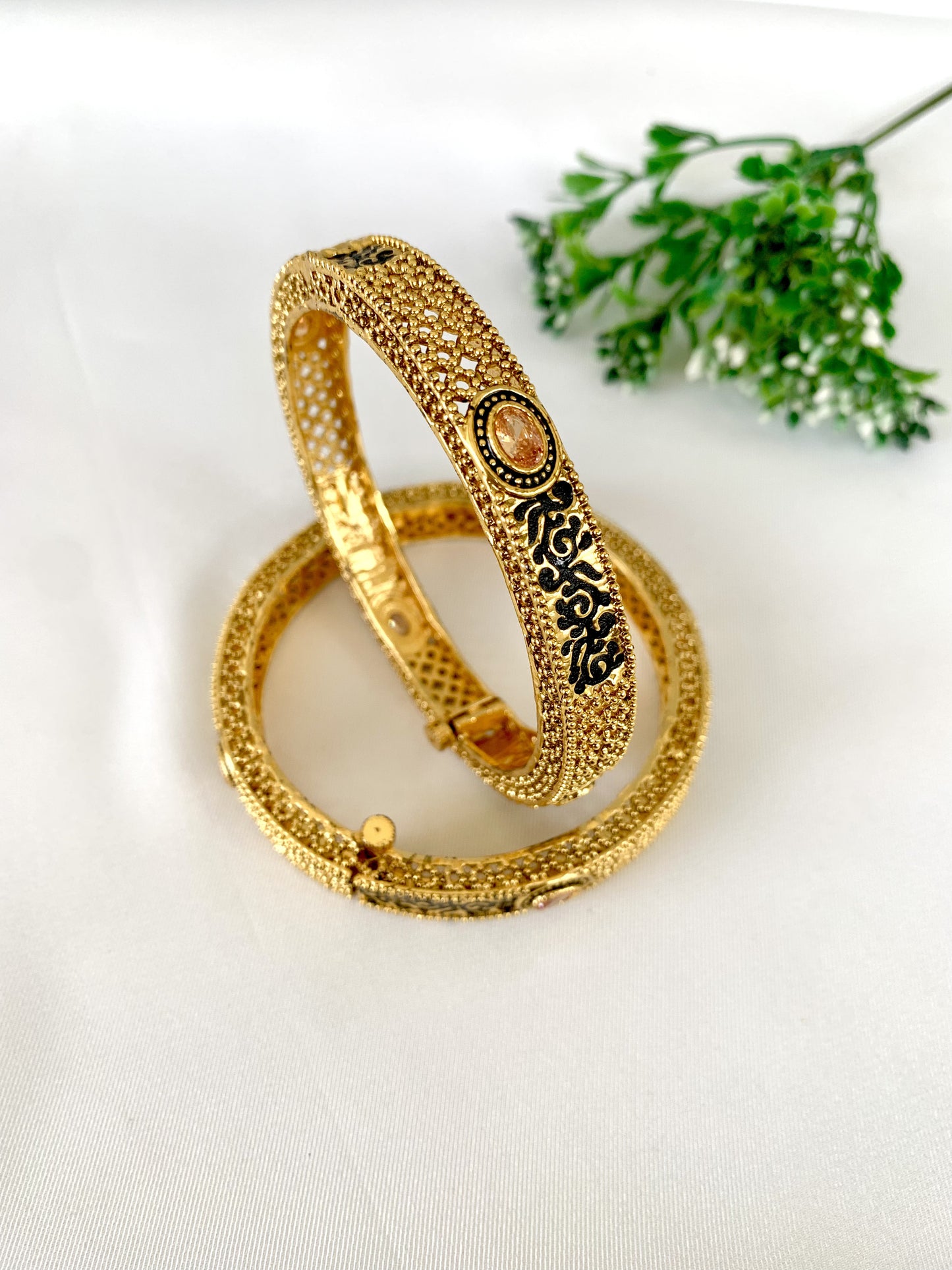Traditional screw bangles with detailed gold texture and black enamel work