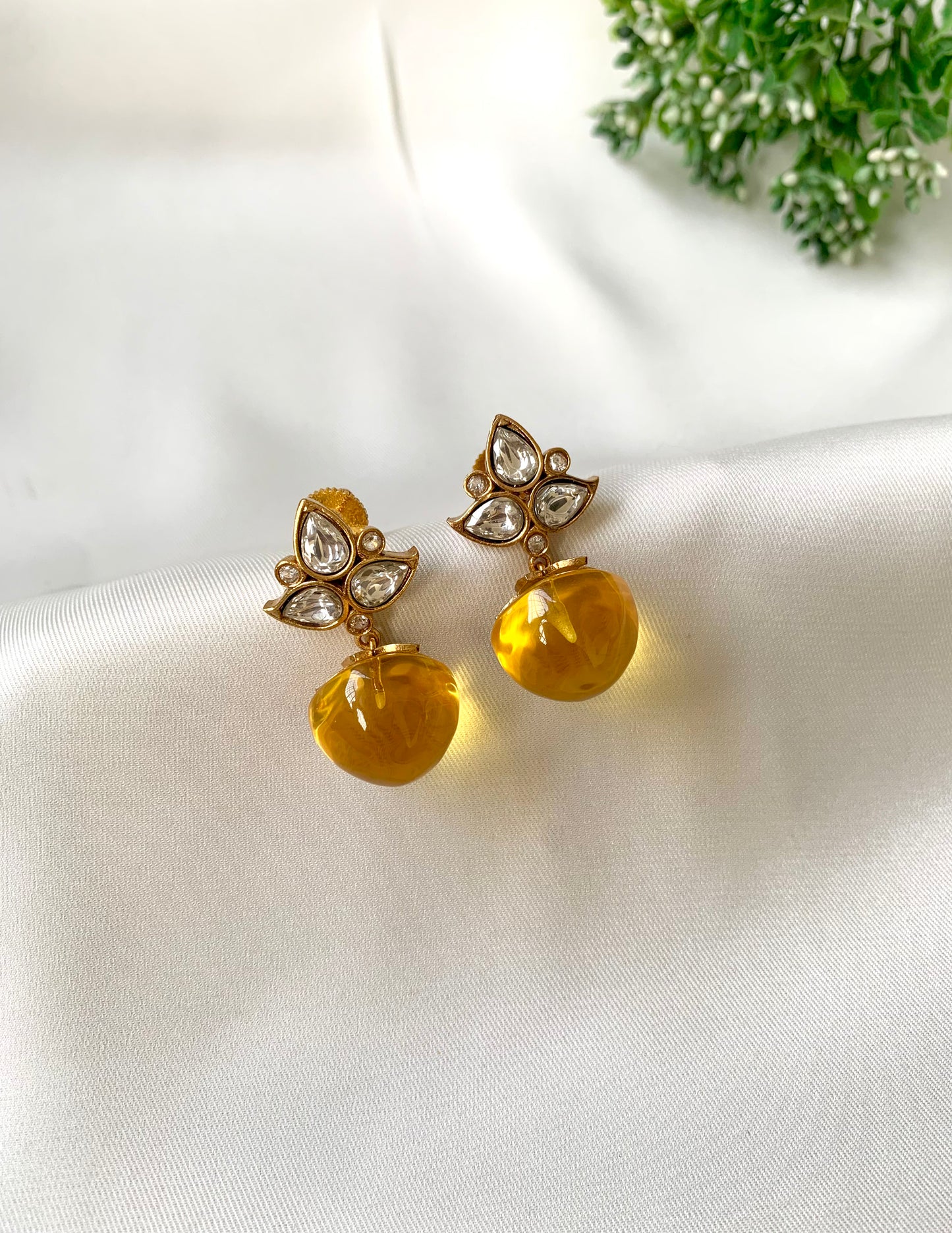 Pair of earrings with yellow gemstones on a white fabric background