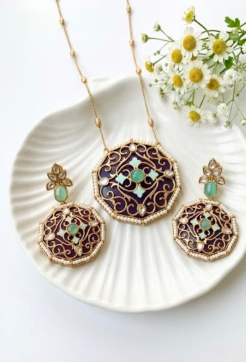 Ornate jewelry set with gold and green accents on a white plate with flowers.
