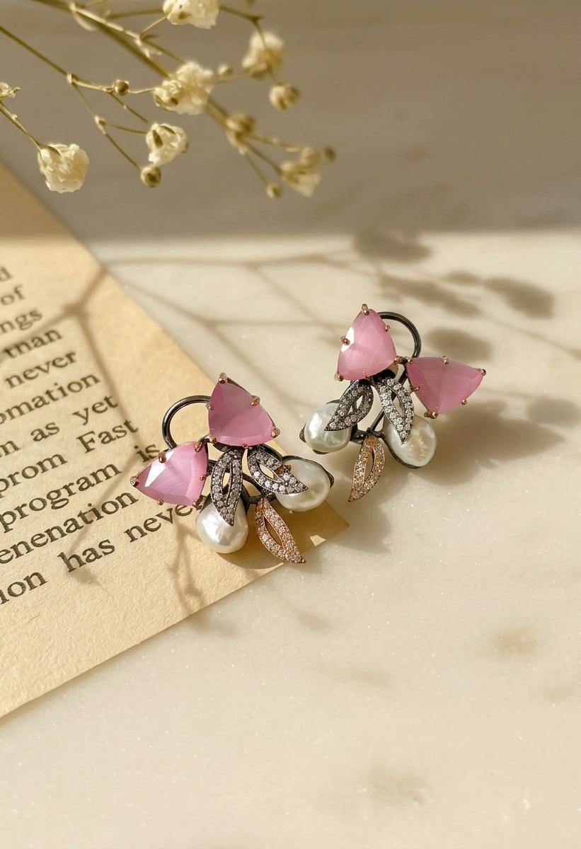 Pair of pink butterfly earrings on a textured surface with dried flowers in the background