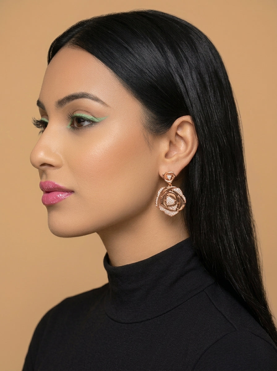 A woman in profile wearing a rose gold rose-shaped dangle earring with a white pearl center, set against a solid beige background.
