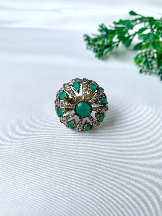 Close-up of Selene Bloom Ring with Semi-Precious Emerald stones and American Diamonds in antique Victorian rhodium finish, displayed on white fabric